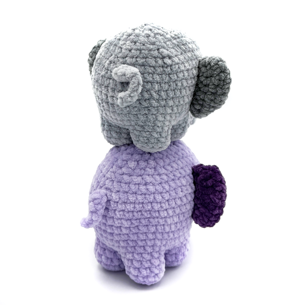 Backsides of 2 Crochet Amigurumi Elephants standing on top of each other. Bottom elephant is purple, top is gray.