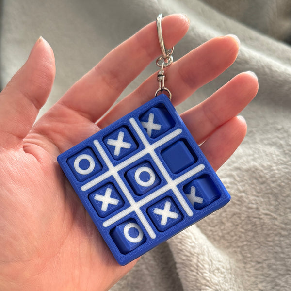 Tic Tac Toe fidget keychain with spinning X's and O's being held