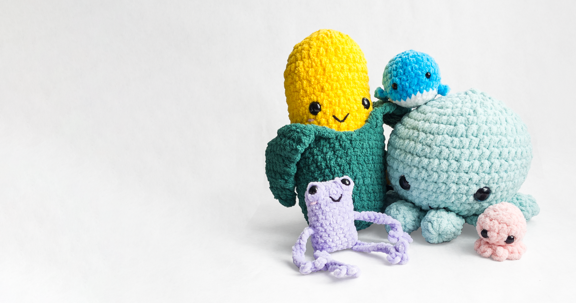 Amigurumi, crochet stuffed animals, mama and baby octopi grouped with a corn, leggy frog, and mini whale