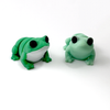 Two 3D printed frog mini fidget creatures -two green frogs facing forward, the one on the left has a white underbelly