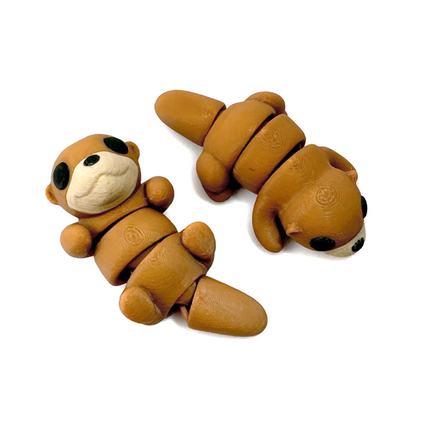 Two 3D printed otter mini fidget creatures one that is belly up and laying on its back, the other on its tummy