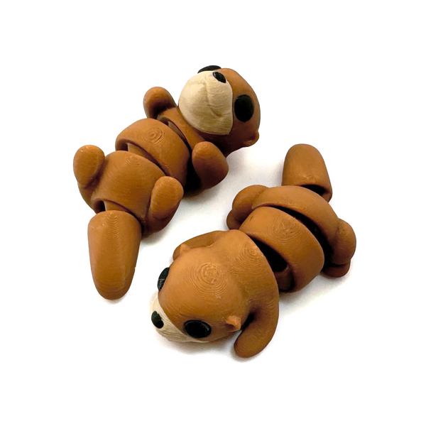 Two 3D printed otter mini fidget creatures one that is belly up and laying on its back, the other on its tummy