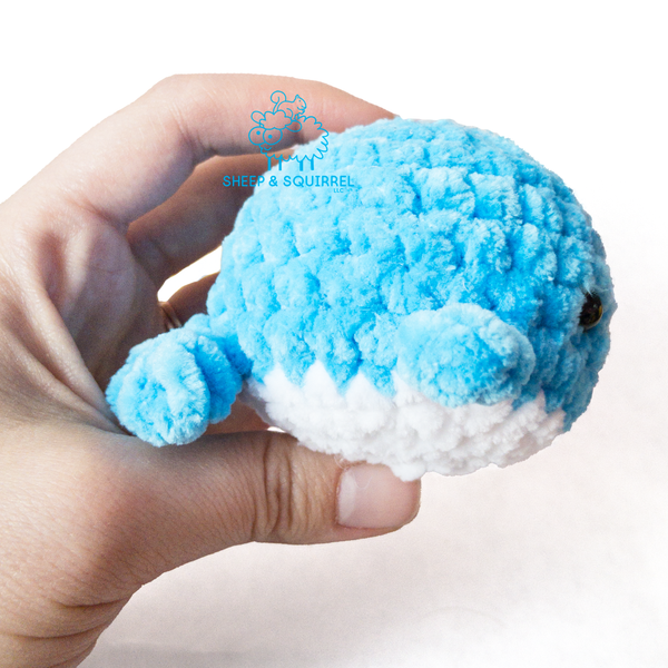 Side view of a little amigurumi crochet stuffed animal whale being held in hand