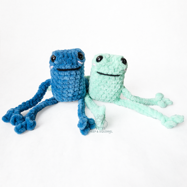 Two crochet amigurumi leggy frogs sitting