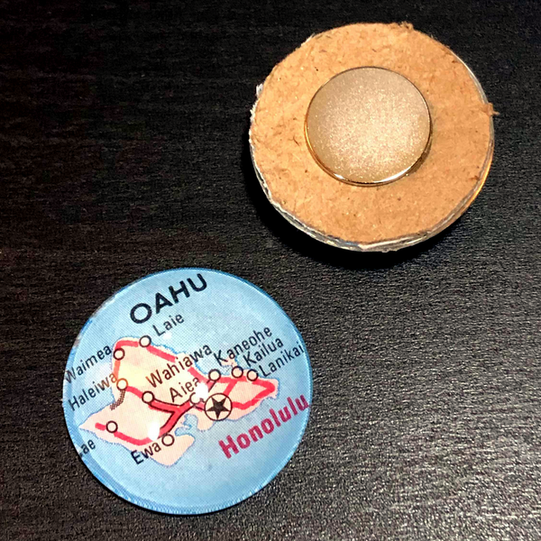 Two 1" glass dome map magnets, one facing up showing the Hawaiian island of Oahu, and the other is upside down showing the neodymium rare earth magnet
