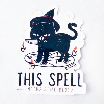 Die cut glossy vinyl sticker featuring a black cat with a witch hat, a knife in its mouth, on a seance circle that says "this spell needs some blood"