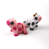 Two 3D printed cow mini fidget creatures - one pink strawberry cow, and one black and white cow