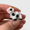 3D printed black and white cow mini fidget creature being held