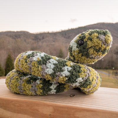 Crochet amigurumi snake on railing outside