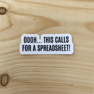 Die cut glossy vinyl sticker that says "oooh... this calls for a spreadsheet!" on wood background